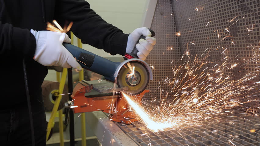 Worker Using Angle Grinder To Cut Metal With Bright Sparks Flying During Industrial Process On Workshop Bench, detailed closeup of construction and engineering work