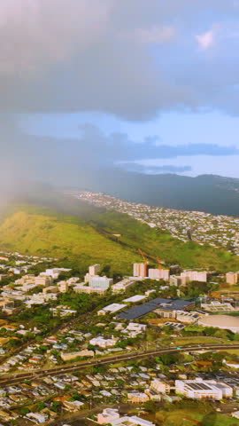 Aerial view of residential buildings on the slopes of a volcano in downtown Honolulu. Rain clouds on the horizon in bright sunlight. Vertical video.