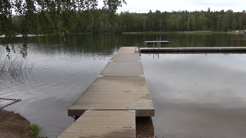 Stockholm, Sweden A man bathes from a wooden pier in a cold rainy Swedish lake.