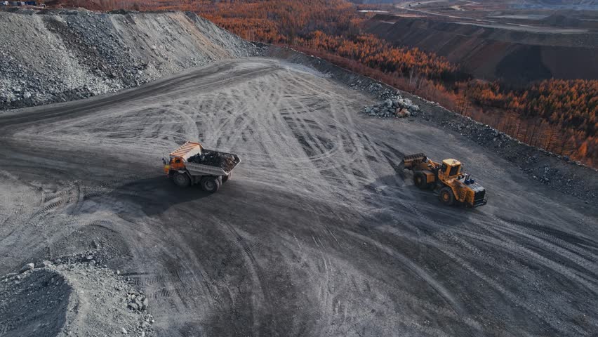 Extractive industry for gold, iron copper ore. Big yellow truck work on Open pit mine, aerial view by drone.