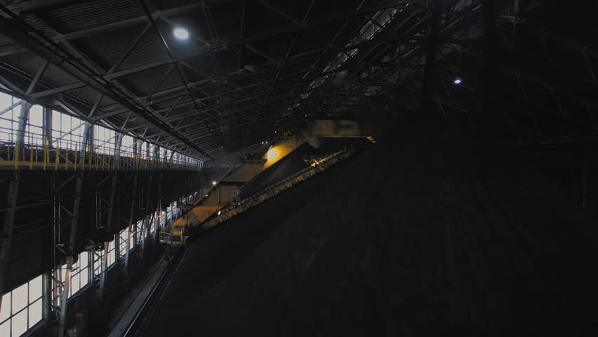 Conveyor loads magnetite large warehouse iron ore at factory on open pit mine.