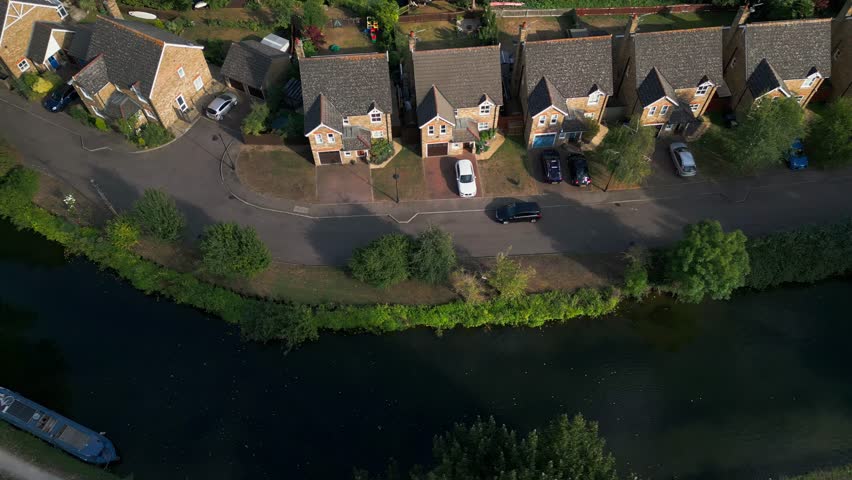 Aerial view of Government Row, Enfield Island Village, with rooftops, streets, and the River Lea Navigation running alongside the residential area.