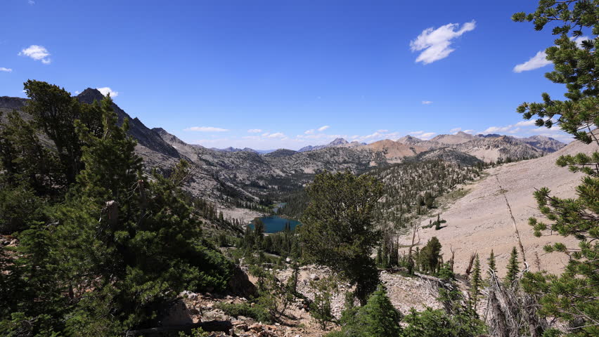 Stunning alpine view from Snowyside Pass in Idaho’s Sawtooth Mountains, where pristine Lake 8779 lies in a rugged wilderness basin beneath a wide blue summer sky.