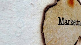 A close-up image of the word marketing printed on a burnt paper - Powered by Shutterstock - Get 15% off with code: PIKWIZARD15