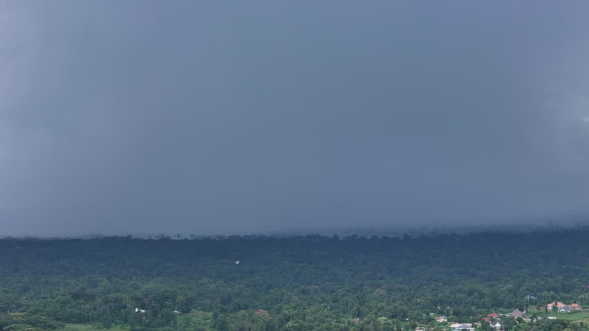 Cloudy sky with a mountain in the background. The sky is dark and the mountain is covered in trees