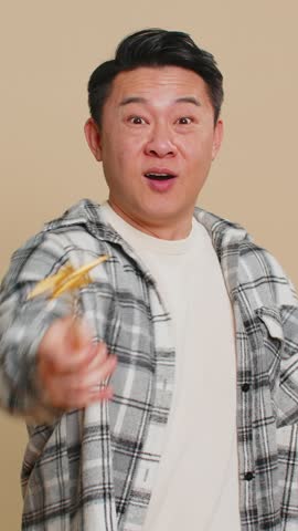 Magician witch Asian middle-aged man gesturing with magic wand fairy stick, making wish come true, casting magician spell, advertising holidays sale discount. Mature Chinese guy on beige background