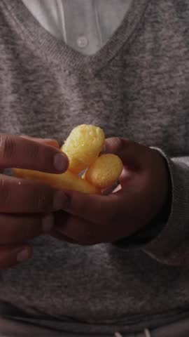 A pair of hands holding yellow snacks that make your hands dirty.