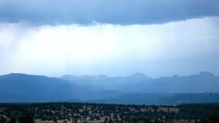 Dramatic mountain landscape with storm clouds and rain in the distance