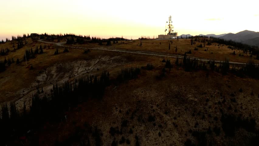 Aerial view of a mountain peak with a communication tower at sunset