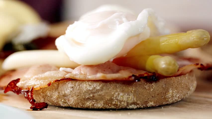 Close up of an egg benedict with bacon and asparagus on a muffin for breakfast