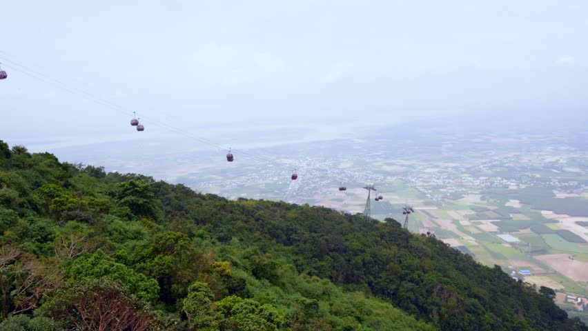 A panoramic view of the landscape from Ba Den Mountain, with a cable car line descending over the lush green mountainside and the flat expanse of Tây Ninh Province below.