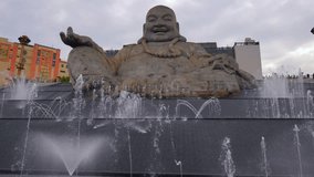 A huge stone Maitreya Buddha statue with a joyful expression sits amidst splashing fountains on Ba Den Mountain, with a temple in the background. - Powered by Shutterstock - Get 15% off with code: PIKWIZARD15