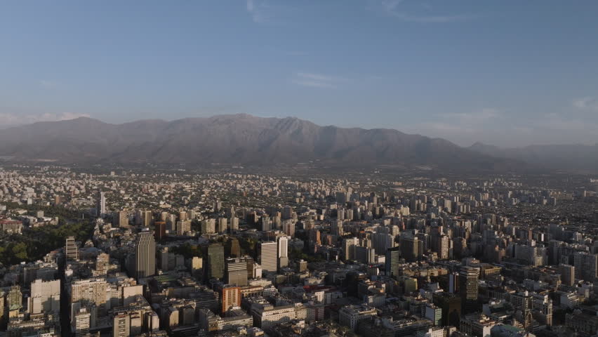 Aerial view of Santiago de Chile with the Andes Mountains in the background on a clear summer day, showcasing the dense urban skyline and the contrast between city and nature