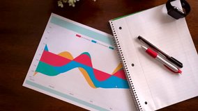 Colorful line chart on paper with notebook and pen, representing financial planning and analysis. - Powered by Shutterstock - Get 15% off with code: PIKWIZARD15