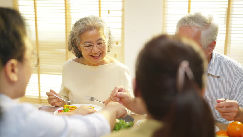 Happy Asian family senior parent and adult child having dinner together at home. Family enjoy weekend activity celebration holiday event meeting, cooking, eating, sharing food and talking together.