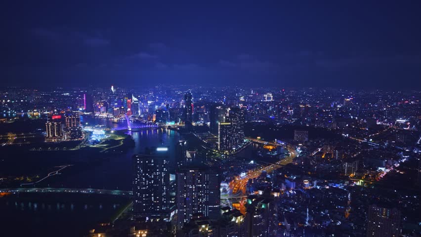 Ho chi minh city and Saigon river in Vietnam, neon illuminated of bridge and business center with skyscrapers, Aerial night view