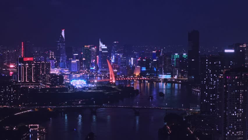Aerial night view Ho chi minh city and Saigon river in Vietnam, illuminated of bridge and business center with skyscrapers