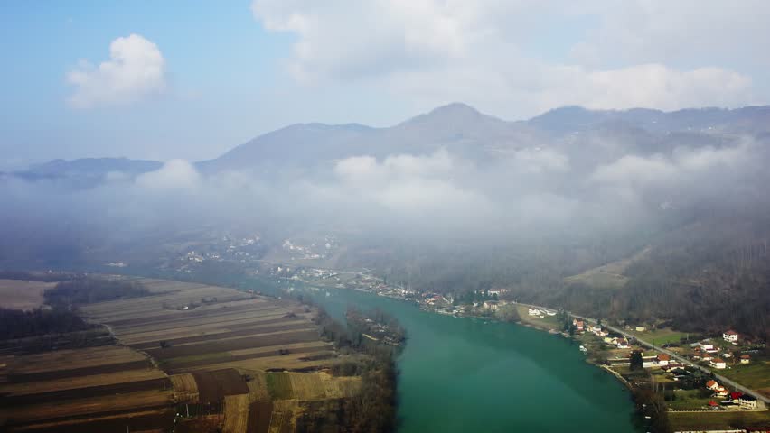 Tranquil river flows through green valleys and misty mountains in a serene landscape