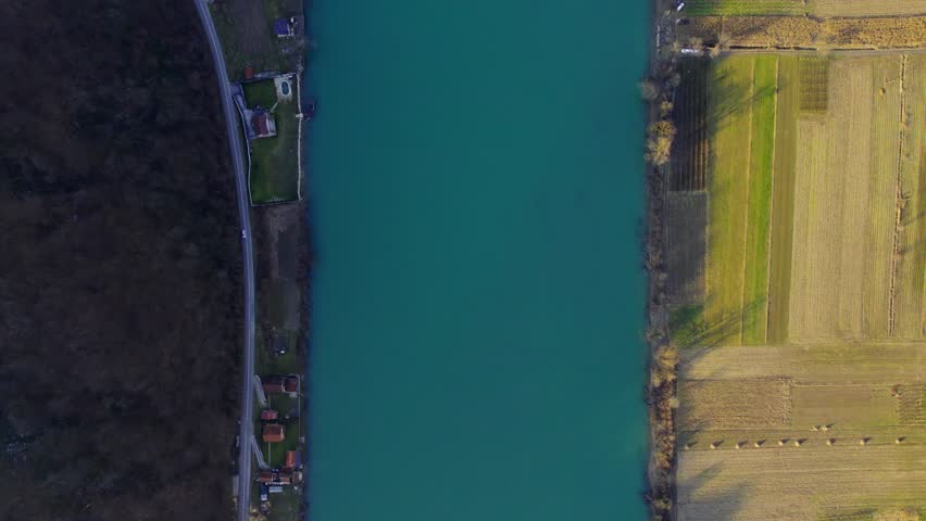 Beautiful aerial view of a serene river flowing beside lush fields and quaint homes at sunrise