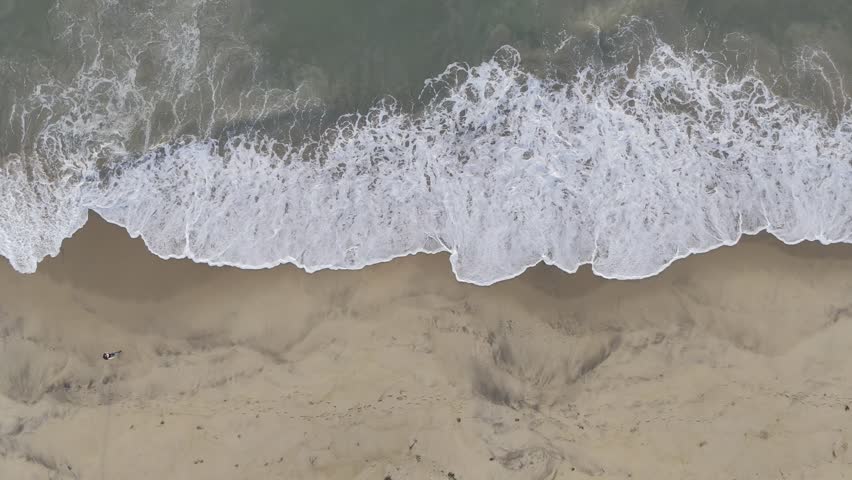"Drone view of strong waves crashing against the sandy Marina Beach shoreline in Chennai, Tamil Nadu, India."