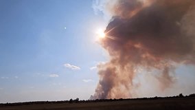 Fire, view from a moving car - a huge column of smoke in the rays of the sun against the background of a blue sky - Powered by Shutterstock - Get 15% off with code: PIKWIZARD15