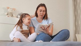 A caregiver helps a small girl read her first book in a bright room. Concept of preschool learning and child development. Bottom view. - Powered by Shutterstock - Get 15% off with code: PIKWIZARD15