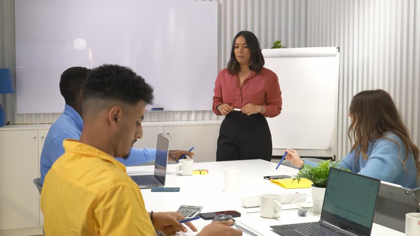 Businesswoman leads a presentation to her team in a modern office, engaging in discussion and collaboration