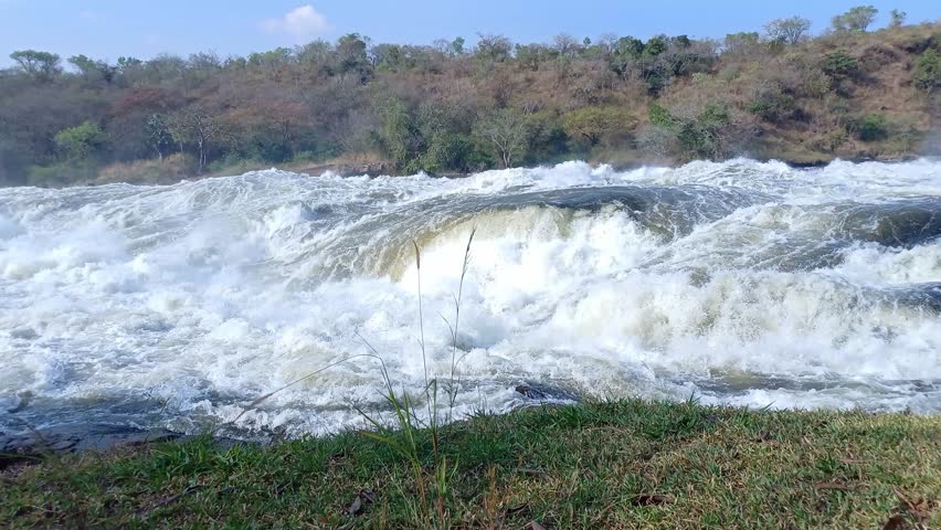 A riverside view of powerful Murchison Falls cascading through rocky terrain in Uganda lush landscape