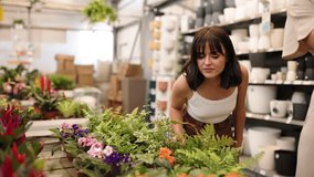 Customers browsing colorful plant selection at garden center, examining flowers on shelves while enjoying shopping experience together - Powered by Shutterstock - Get 15% off with code: PIKWIZARD15