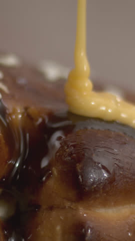 Slow-motion shot of rich chocolate pouring over a moist lemon cupcake on a wooden table, creating a decadent dessert scene perfect for gourmet bakery branding and indulgent food visuals.
