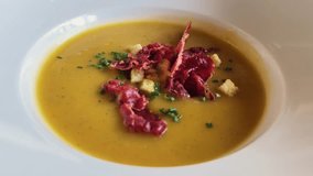 Pumpkin cream soup with jamon, herbs and croutons on a wooden table in a restaurant. - Powered by Shutterstock - Get 15% off with code: PIKWIZARD15