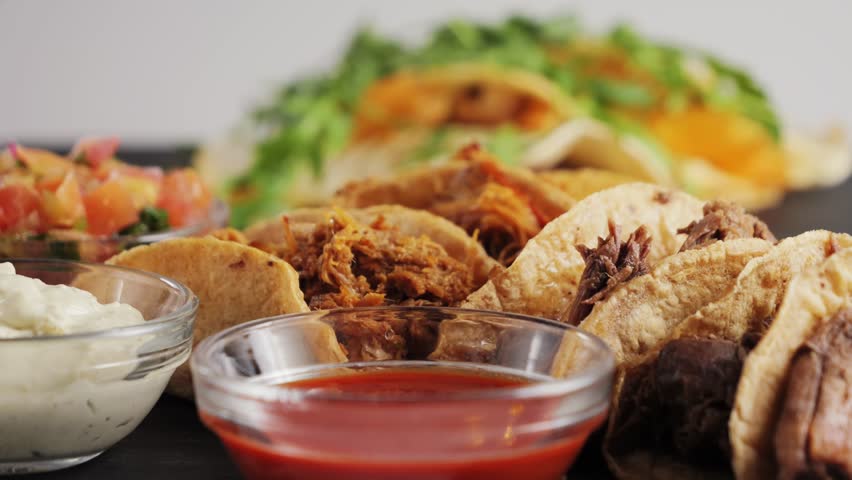Delicious tasty taco with stewed beef and beans, spicy sauce Valentina and creamy sauce. Mexican cuisine concept.