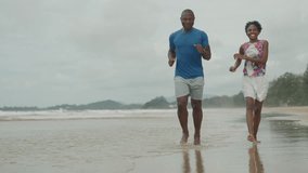 Joyful African American Couple Running Playfully Along the Seashore, Happy Black Man and Woman Enjoying a Romantic Beach Vacation Together - Powered by Shutterstock - Get 15% off with code: PIKWIZARD15
