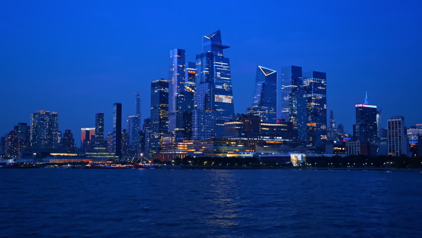 Skyline of luminous New York, USA at dusk time. View from the boat travelling by the river.