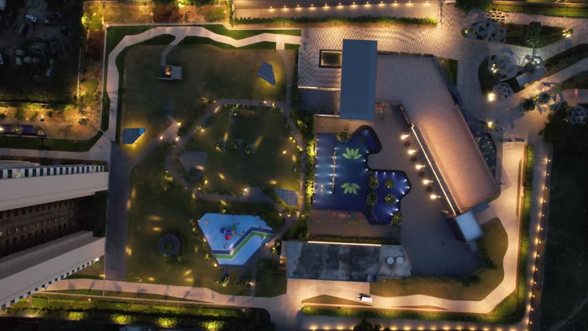 Aerial drone shot straight down into luxurious condominium society housing complex with sports area, pool with man swimming, extensive gardens and walkways showing the luxurious life in Gurgaon delhi