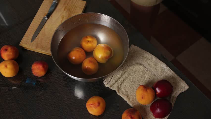 Hands Washing Fresh Peaches in a Bowl for Fruit Preparation