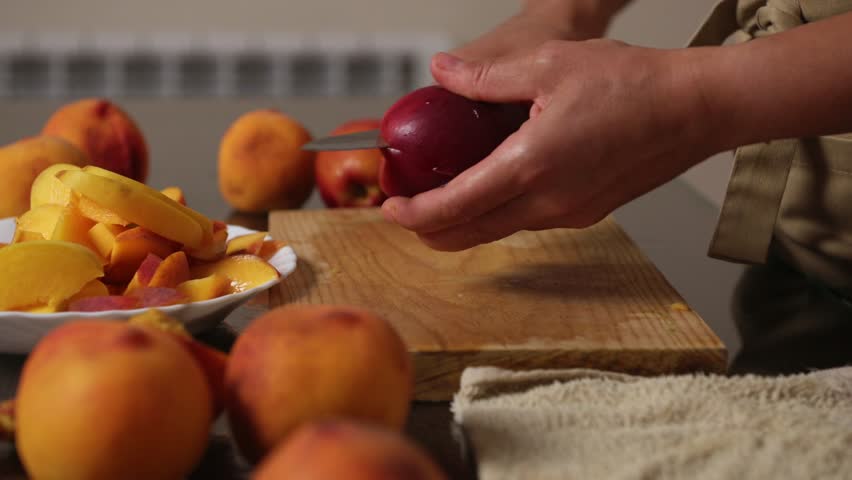 Slicing Fresh Peaches on a Wooden Board for a Delicious Homemade Dish