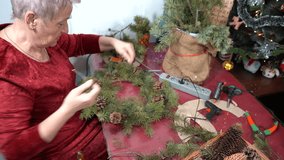 Grandmother making Christmas wreath, branches and cones. Elderly woman decorate spruce. Senior winter activities. DIY craft - Powered by Shutterstock - Get 15% off with code: PIKWIZARD15