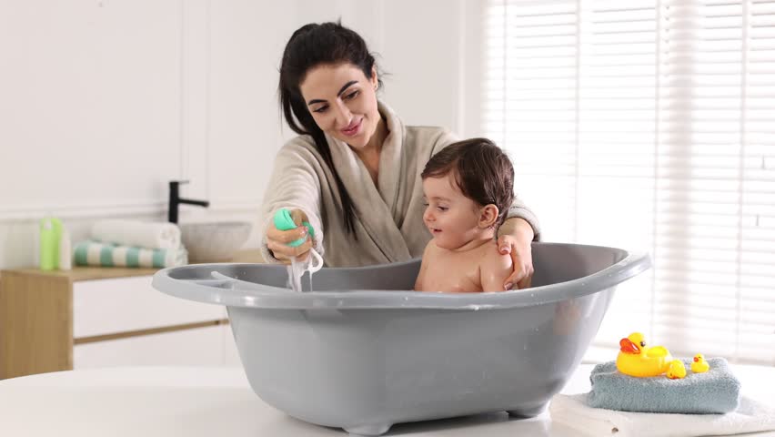 Mother bathing her little baby at home