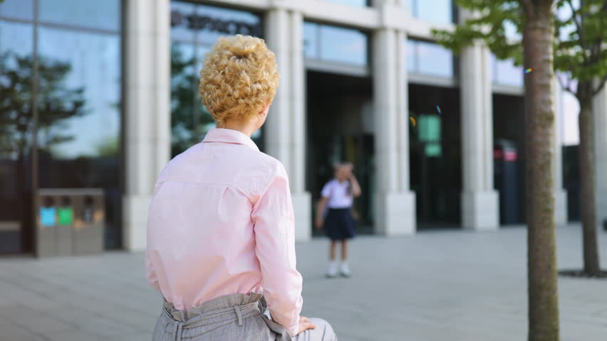 A mom and her daughter embrace warmly outside of a school, conveying a moment of love and connection.