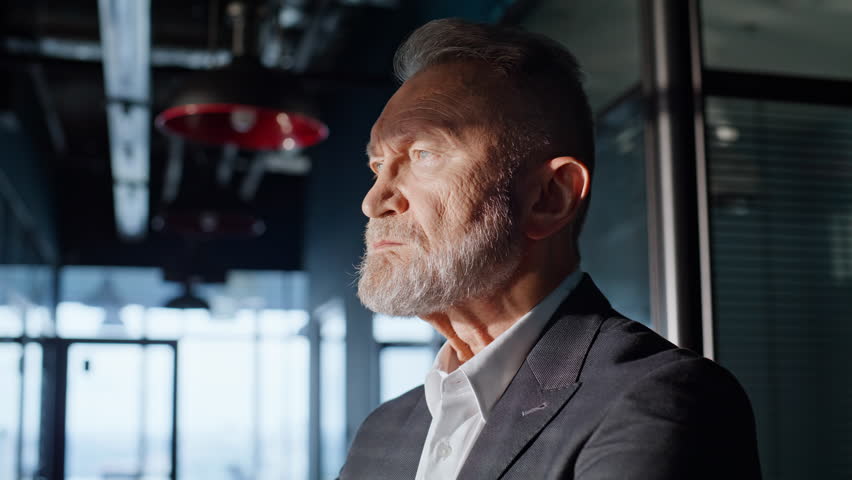 Frustrated businessman hiding face in palm worried corporate crisis in office corridor closeup. Sad elderly manager standing in modern hall feeling stress. Troubled gray-hair investor losing money.