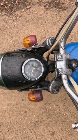 vertical video Old and rusty motorcycle showing speedometer and turn signals on dirt road