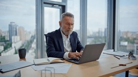 Mature manager looking laptop planning business project at modern workplace closeup. Bearded businessman working computer at light office. Aged man entrepreneur browse app reading papers on desk. - Powered by Shutterstock - Get 15% off with code: PIKWIZARD15