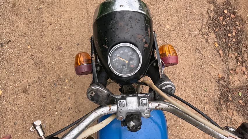 Old and rusty motorcycle showing speedometer and turn signals on dirt road