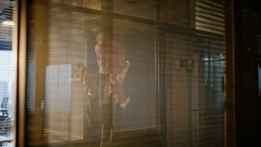 Businessman recording voice message on smartphone walking business hall in evening sunlight closeup. Aged manager creating audio email on cellphone by office glass wall. Bearded man boss talking phone