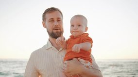 Father kissing his baby boy on the beach during sunset, enjoying a joyful moment together by the ocean - Powered by Shutterstock - Get 15% off with code: PIKWIZARD15