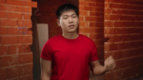 Young man blowing kiss at indoor construction site, holding keys, wearing red shirt, against brick wall backdrop, expressing affection in industrial setting with casual demeanor. - Powered by Shutterstock - Get 15% off with code: PIKWIZARD15