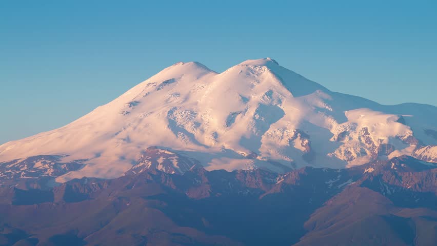 4k, A panoramic view of the snow-capped peaks of Mount Elbrus, the highest point of the European continent, against a clear blue sky, at daytime, Stavropol Krai, Russia