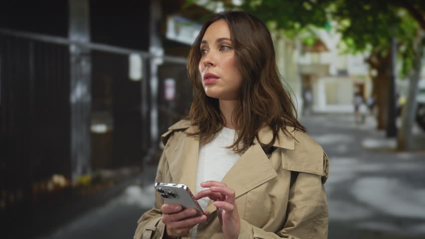 Woman using smartphone on urban city street, focused and engaged.