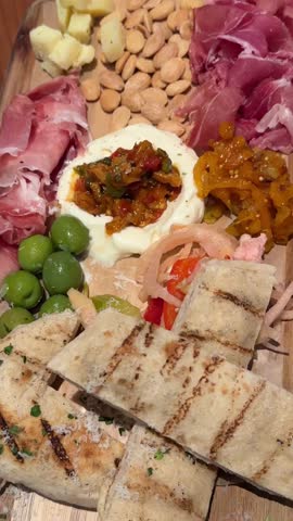 Gourmet charcuterie board with assorted meats, cheeses, olives, and spreads in closeup view